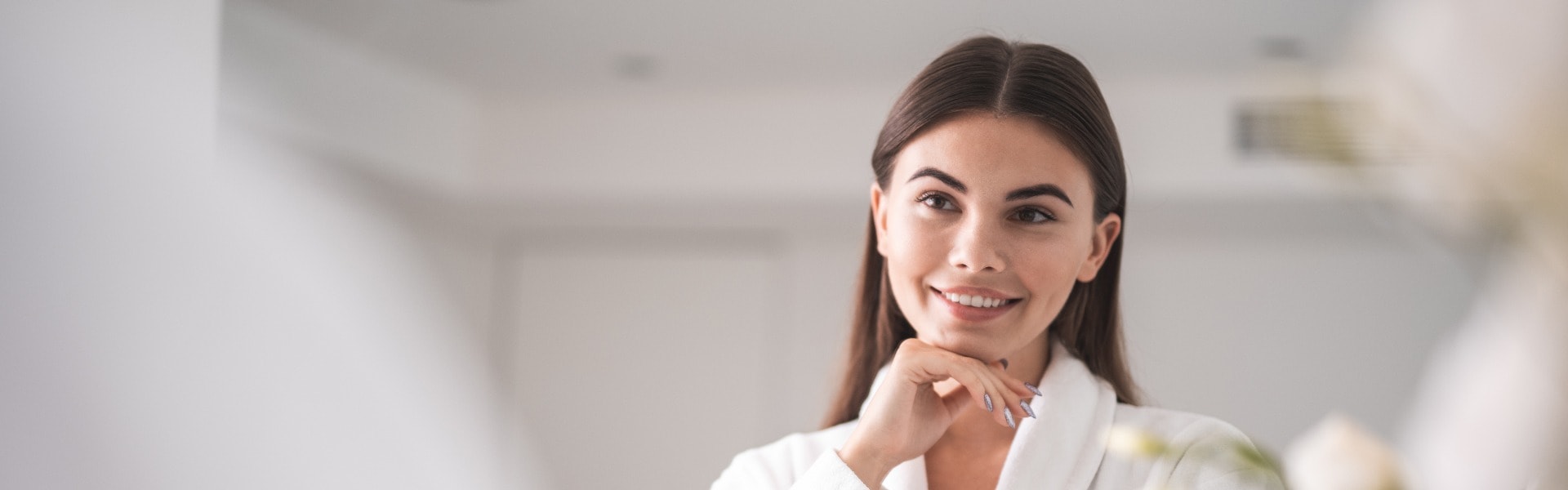 I am so beautiful. Portrait of optimistic lady looking at mirror while touching chin with arm. She standing in room